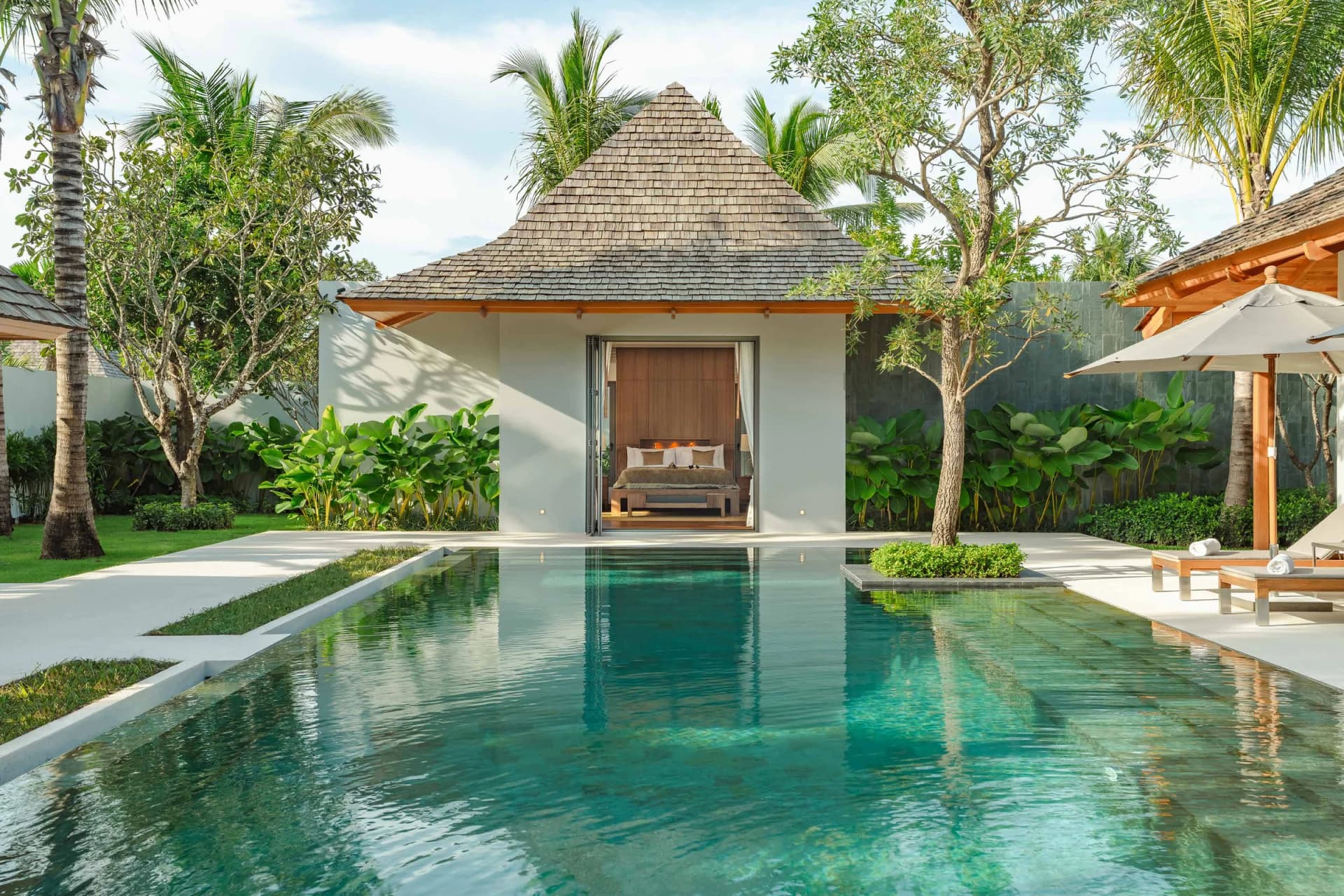 Une villa Anchan : un pavillon de chambre à toit en bardeaux au-dessus d’une piscine turquoise